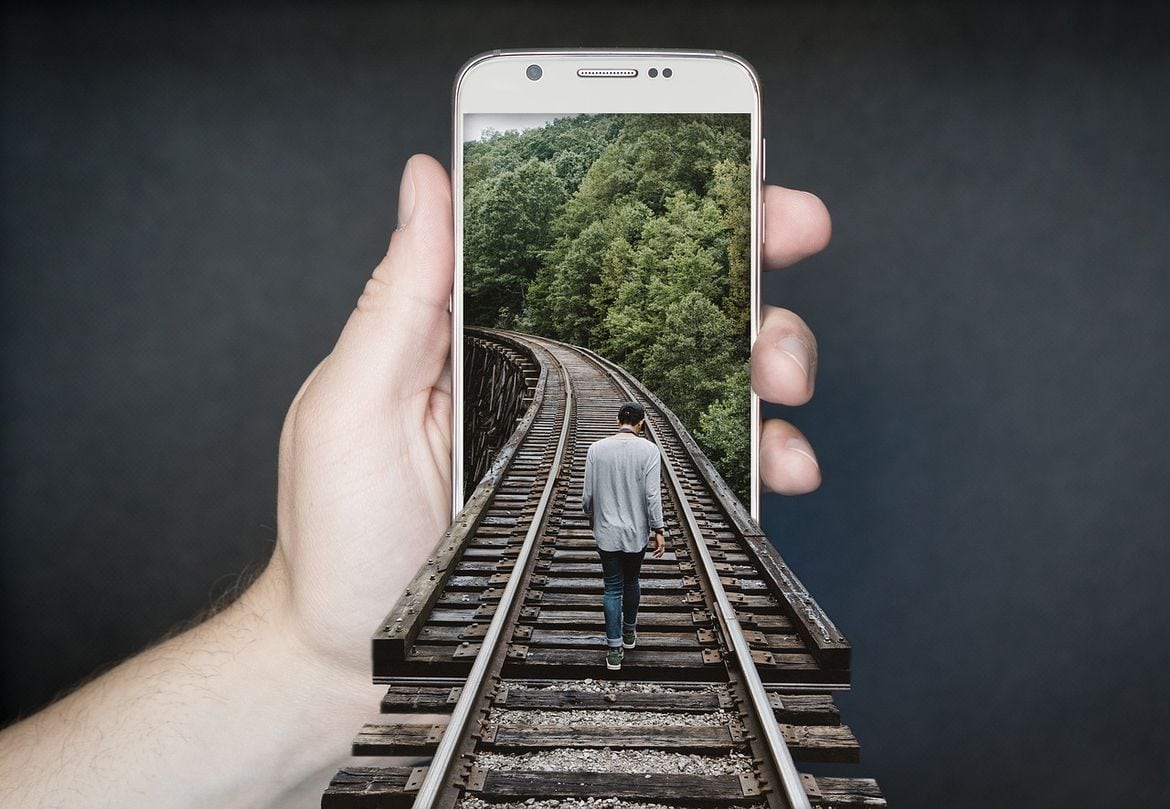 eco friendly apps with man on railroad tracks walking into smartphone