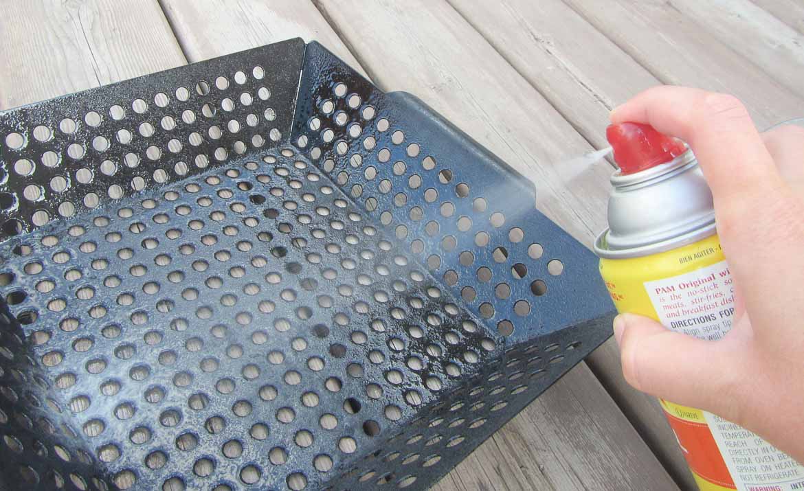 spraying grill basket with cooking oil