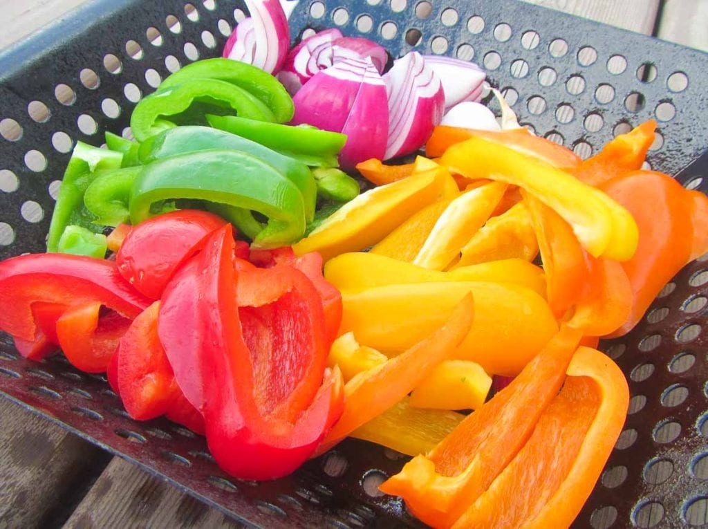 red, yellow, green and orange pepper with purple onion in grill basket
