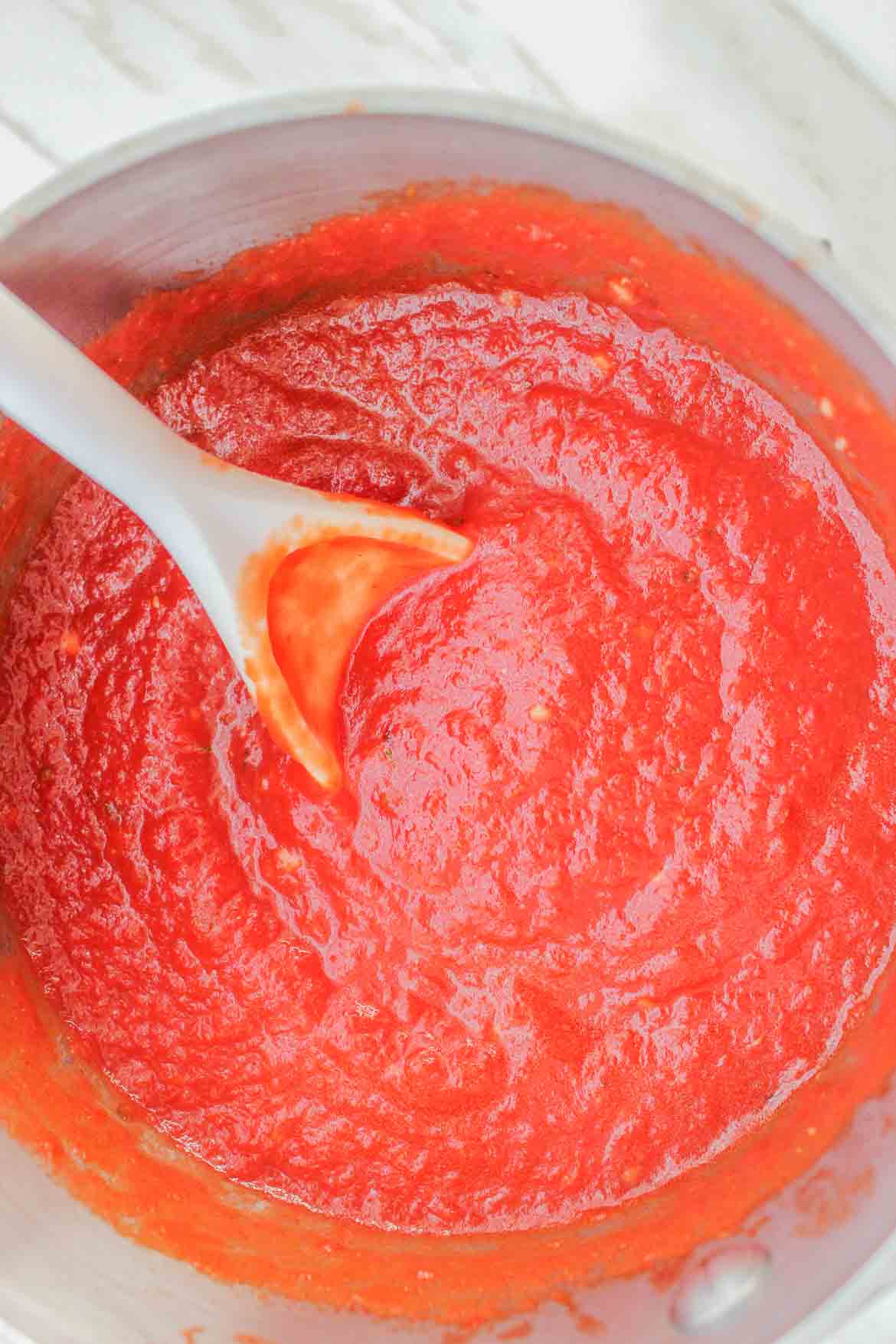 stirring homemade pizza sauce with fresh tomatoes in pot