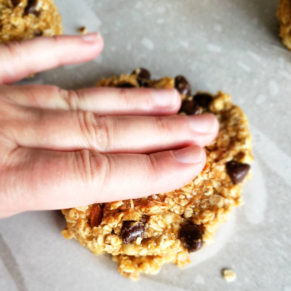 pressing out cookies on parchment paper for banana breakfast cookies