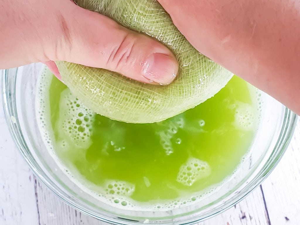 squeezing juiced celery in a cheesecloth