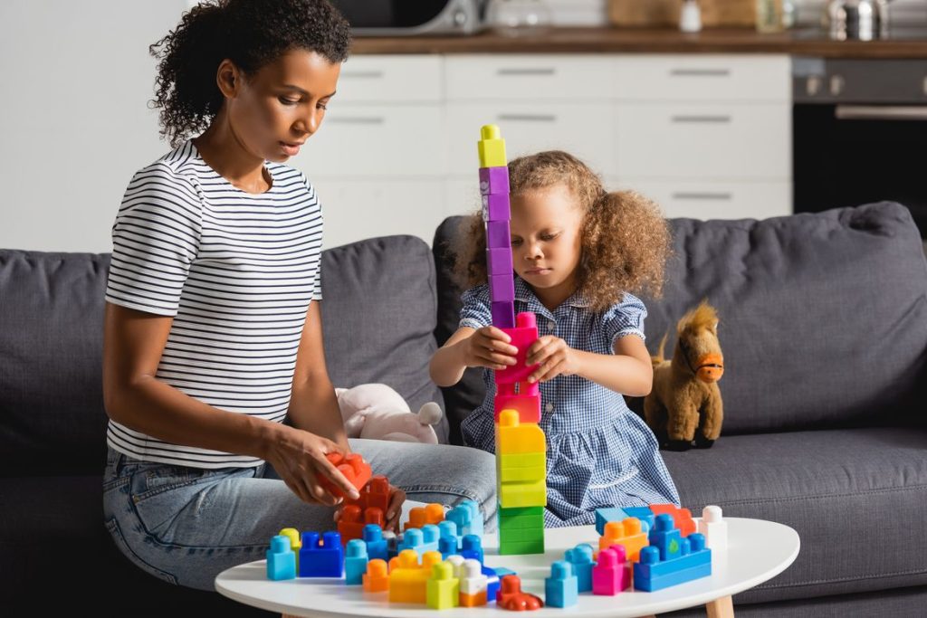 nanny and young girl building a tower