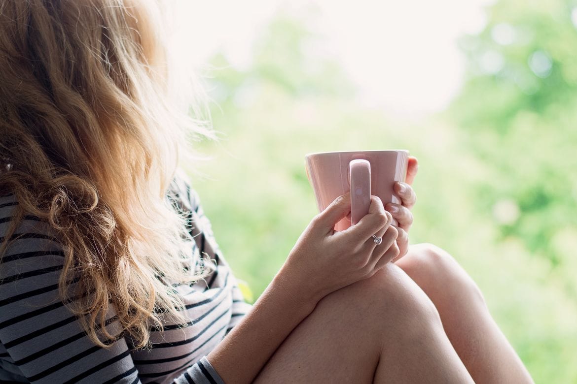 Peaceful woman relaxing at home with cup of tea