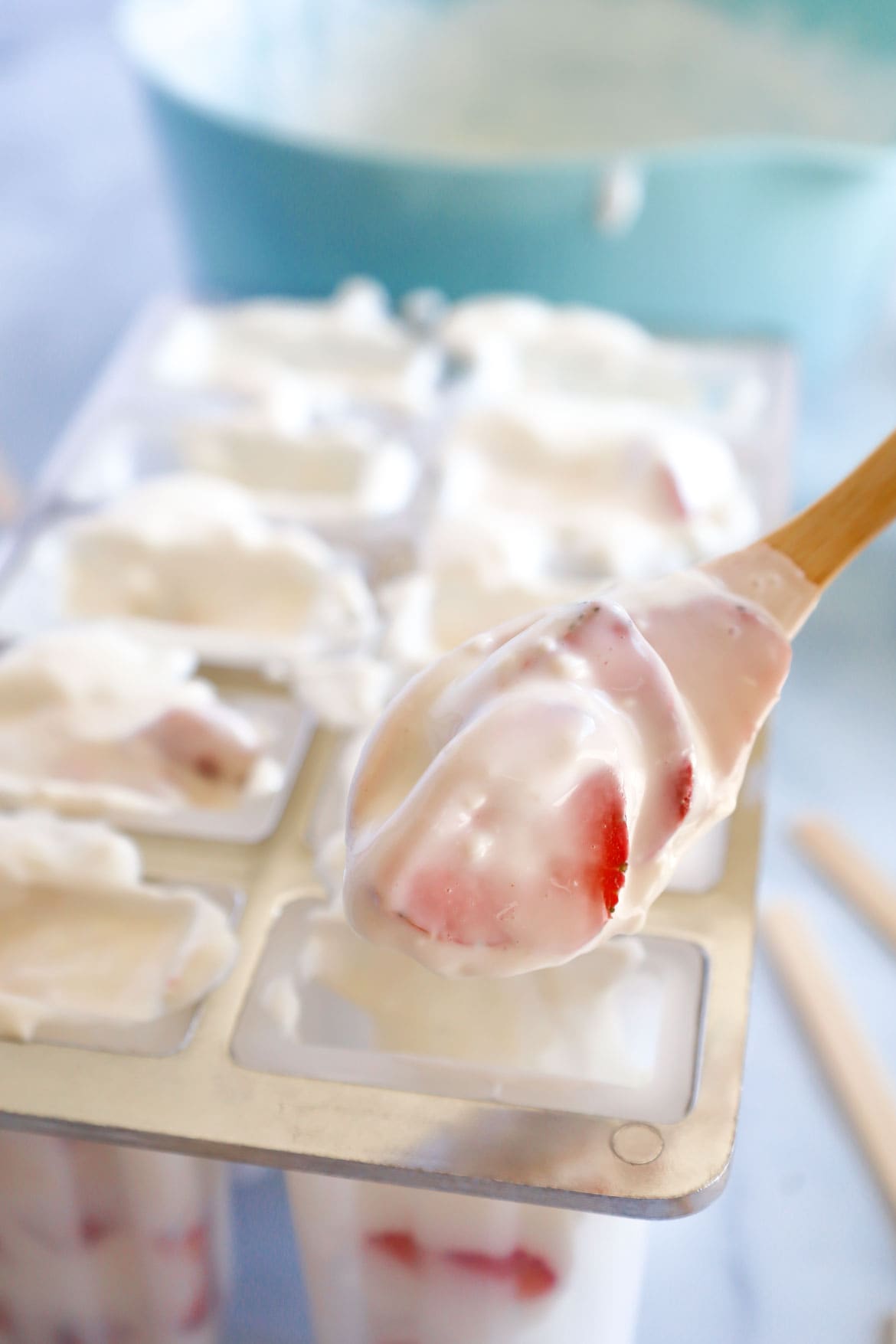 Spooning strawberry cheesecake mixture into popsicle molds