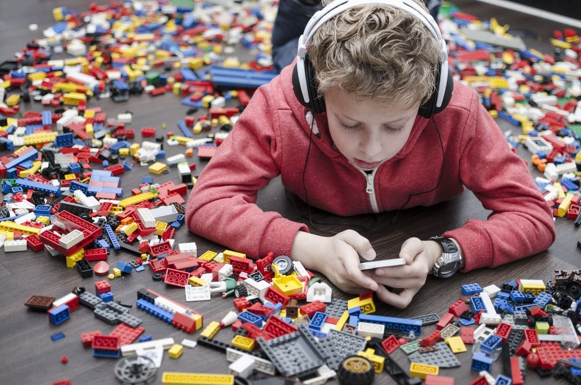 Young boy with headphones playing lego
