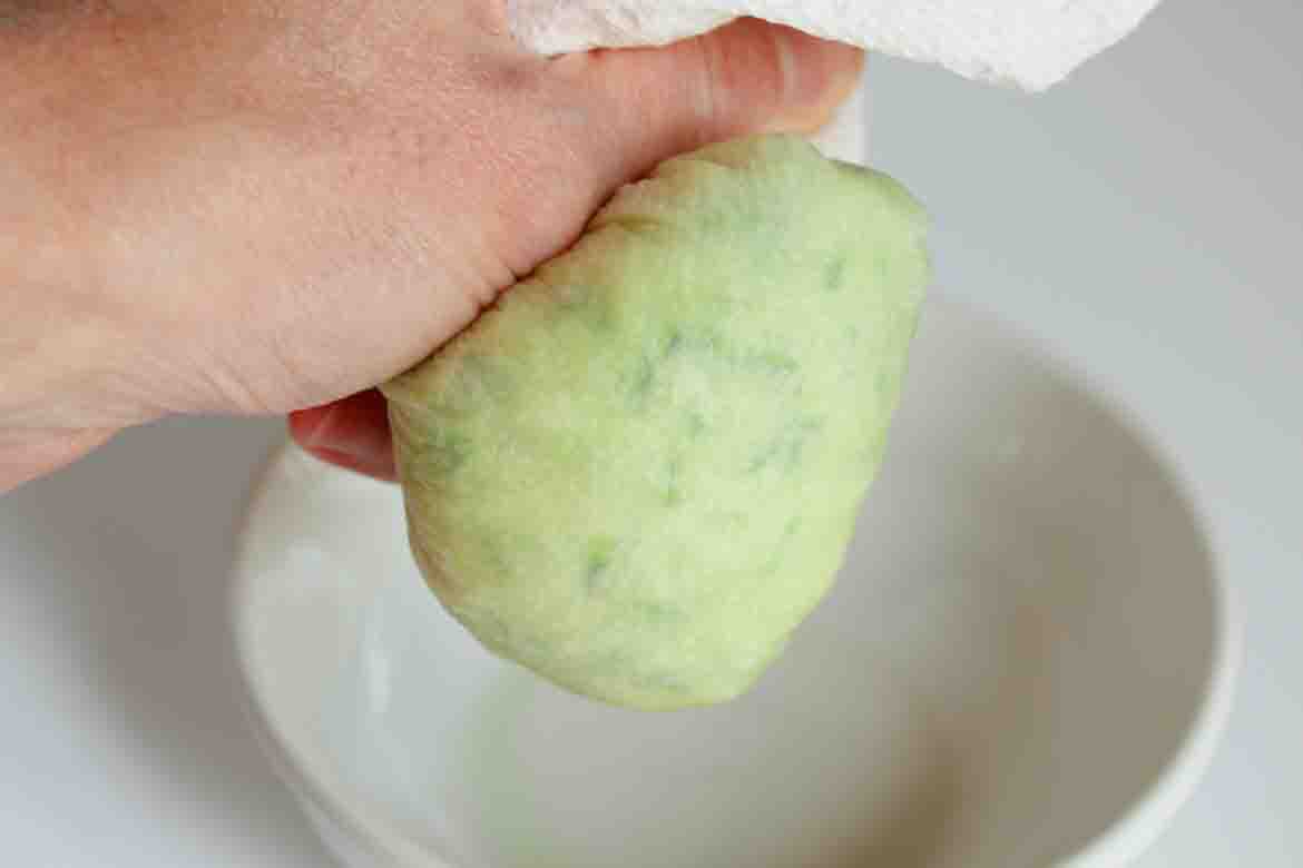 squeezing liquid out of zucchini with a cheesecloth