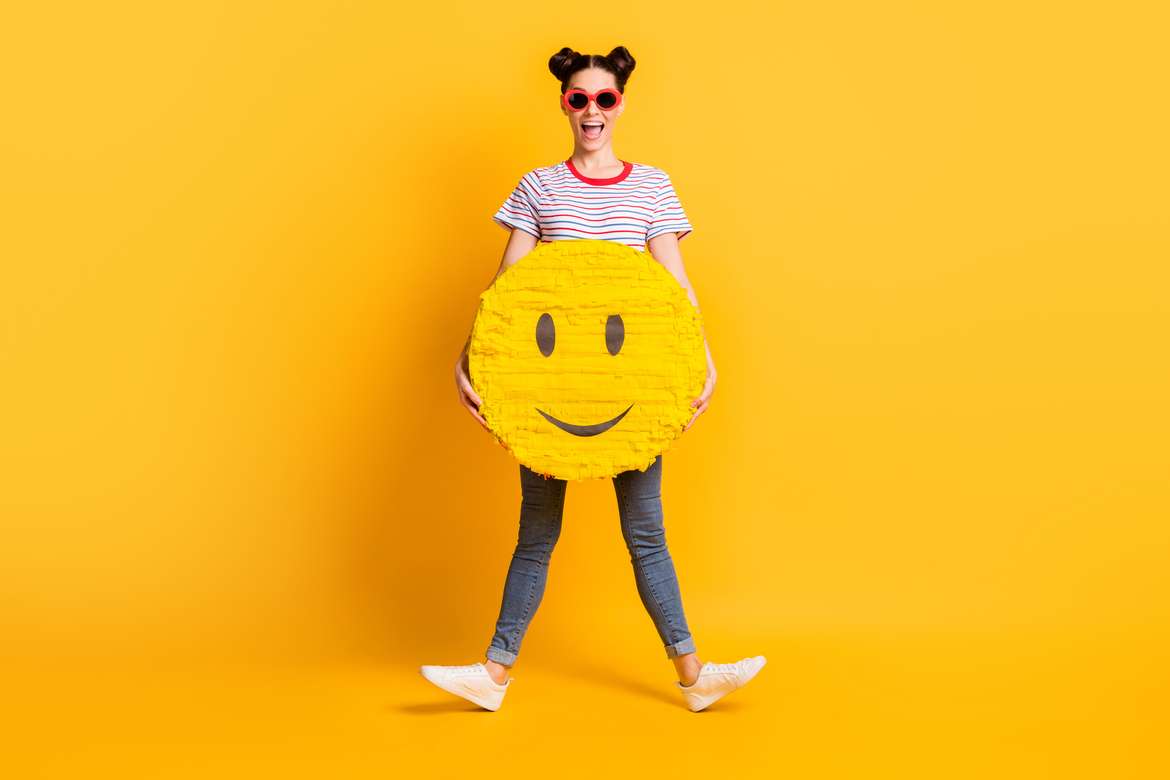 Emojis Parents Should Know - young woman on yellow background with happy emoji