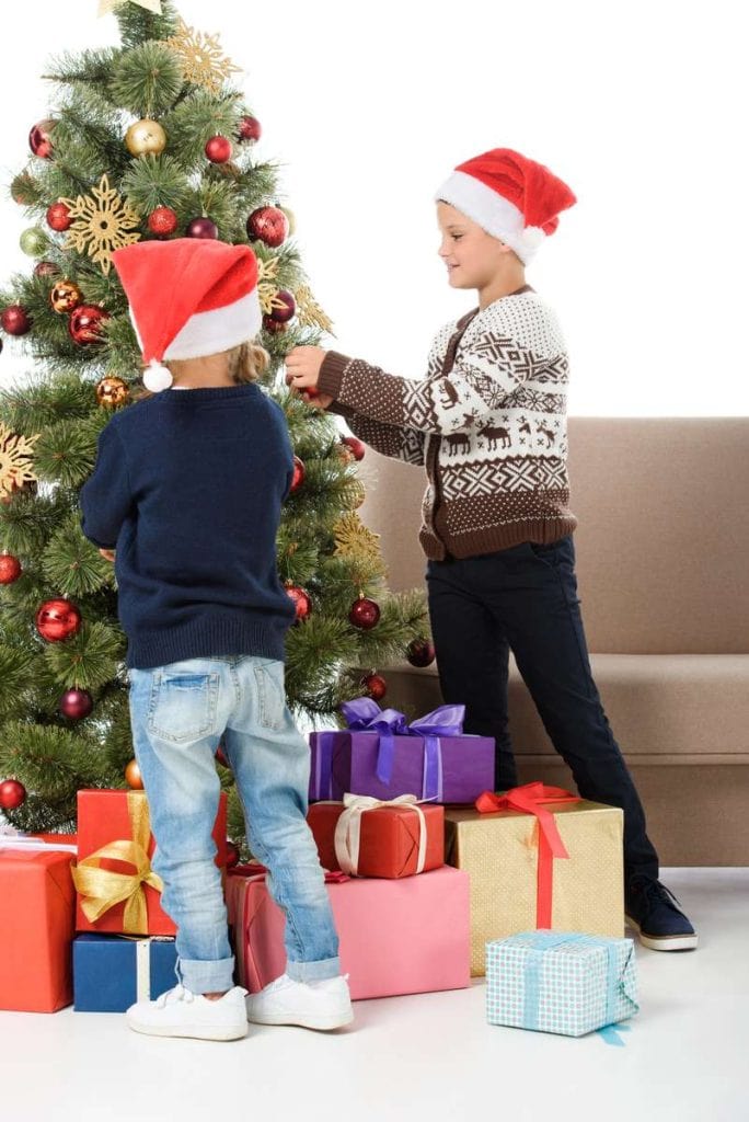 Children in santa hat decorating christmas tree DP