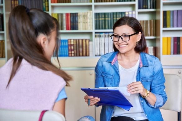 Smiling school counselor holding a binder with student