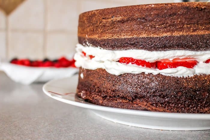 ready to frost cake with whipped cream frosting on chocolate cake with fresh berries