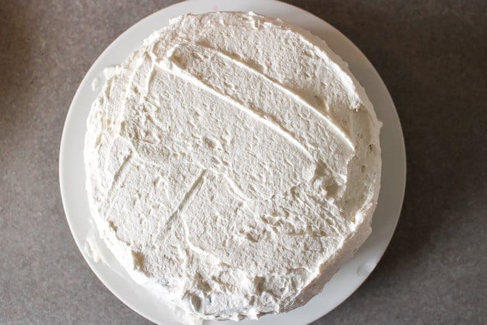 whipped cream frosting on chocolate cake with fresh berries